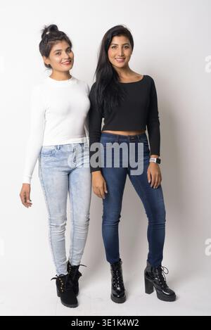 Studio-Aufnahme von zwei jungen schönen persischen Frauen zusammen als Schwestern vor weißem Hintergrund Stockfoto