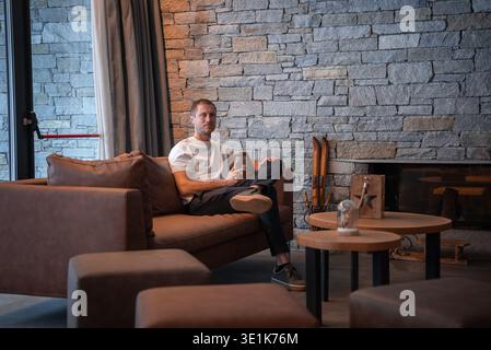 Mann ruht auf Ledersofa am Glaskamin in San Domenico Stockfoto