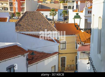 Ferragudo, Algarve, Portugal.26. september 2020. Traditionelle weiße Häuser mit Ziegeldächern in engen Gassen, dekoriert mit Bougainvillea-Blumen im Th Stockfoto
