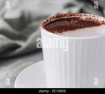 Gemütliche Szene mit einer weißen Tasse Cappuccino mit Schaumkunst und Grün Stockfoto