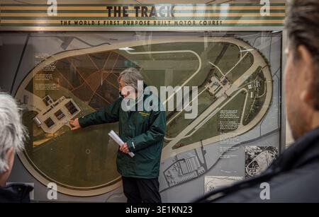 WEYBRIDGE, SURREY, Großbritannien - Ein Museumsführer zeigt auf eine große historische Karte des ursprünglichen Brooklands Motor Course im Brooklands Museum Stockfoto