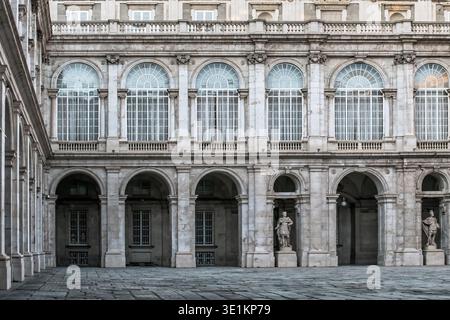 Innenhof des Königspalastes in Madrid mit Bogenfenstern und klassischen Statuen im unteren Stockwerk. Madrid, Spanien - 30. November 2021 Stockfoto