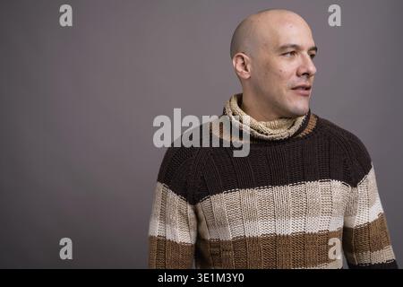 Studio shot der stattliche Mann mit Glatze rollkragen pullover gegen grauer Hintergrund Stockfoto
