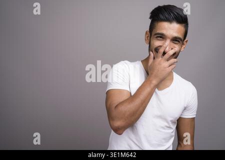 Studio shot der jungen schönen persischen Mann gegen grauer Hintergrund Stockfoto
