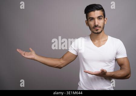 Studio shot der jungen schönen persischen Mann gegen grauer Hintergrund Stockfoto
