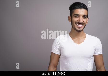 Studio shot der jungen schönen persischen Mann gegen grauer Hintergrund Stockfoto
