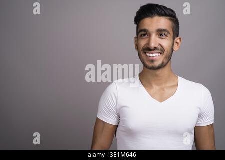 Studio shot der jungen schönen persischen Mann gegen grauer Hintergrund Stockfoto