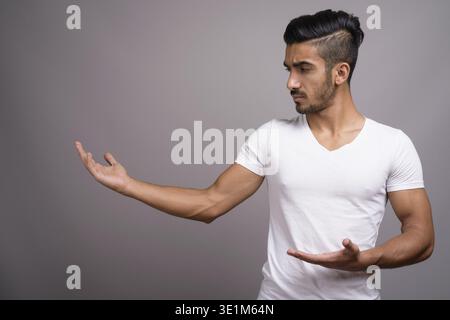 Studio shot der jungen schönen persischen Mann gegen grauer Hintergrund Stockfoto