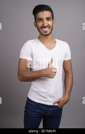 Studio shot der jungen schönen persischen Mann gegen grauer Hintergrund Stockfoto