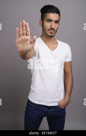 Studio shot der jungen schönen persischen Mann gegen grauer Hintergrund Stockfoto