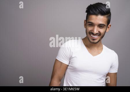 Studio shot der jungen schönen persischen Mann gegen grauer Hintergrund Stockfoto
