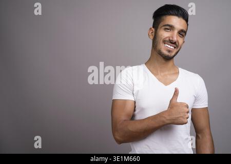 Studio shot der jungen schönen persischen Mann gegen grauer Hintergrund Stockfoto