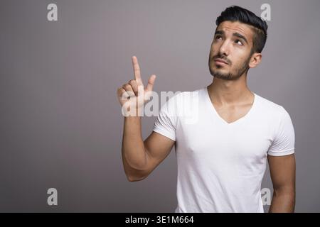 Studio shot der jungen schönen persischen Mann gegen grauer Hintergrund Stockfoto
