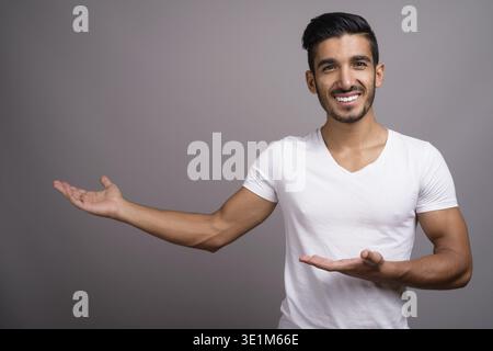 Studio shot der jungen schönen persischen Mann gegen grauer Hintergrund Stockfoto