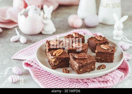 Kleine Stücke hausgemachter Pecan Schokolade Brownies auf einem grauen Tisch mit osterdekoration Stockfoto