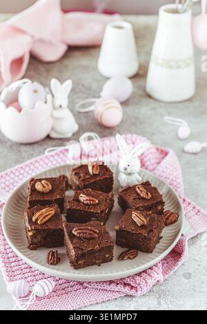 Kleine Stücke hausgemachter Pecan Schokolade Brownies auf einem grauen Tisch mit osterdekoration, vertikal Stockfoto