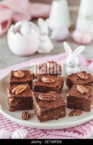 Kleine Stücke hausgemachter Pecan Schokolade Brownies auf einem grauen Tisch mit osterdekoration, vertikal Stockfoto