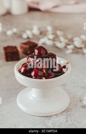 Hausgemachter Gluten- und zuckerfreier Brownie mit Kirschen auf weißem Mini-Kuchen-Teller Stockfoto