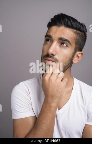 Studio shot der jungen schönen persischen Mann gegen grauer Hintergrund Stockfoto