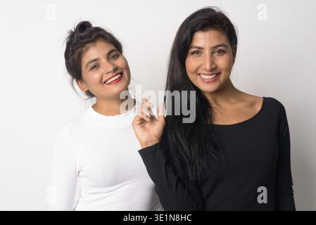 Studio-Aufnahme von zwei jungen schönen persischen Frauen zusammen als Schwestern vor weißem Hintergrund Stockfoto
