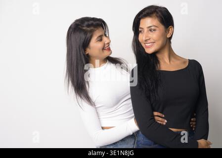 Studio-Aufnahme von zwei jungen schönen persischen Frauen zusammen als Schwestern vor weißem Hintergrund Stockfoto