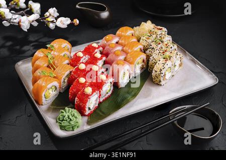Verschiedene Sushi-Brötchen, kunstvoll mit Garnituren auf schwarzem Hintergrund Stockfoto