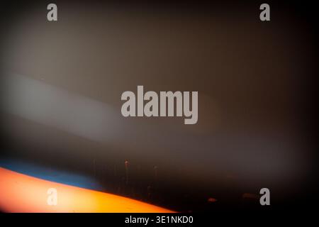 Abstraktes Bild mit unscharfen Lichtstreifen in Orange und Blau vor dunklem Hintergrund, die ein Gefühl von Tiefe und Bewegung in minimalistischem Stil schaffen Stockfoto