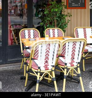 Pariser Bistro mit leeren Tischen und ikonischen französischen Café-Stühlen auf dem Bürgersteig, die typisch europäischen urbanen Lebensstil widerspiegeln Stockfoto