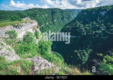 Eine Hochwinkelperspektive mit Blick hinunter in einen üppigen, grünen Canyon, der dicht mit Laubwäldern bedeckt ist. Scharfe Kalksteinformationen im Vorgrou Stockfoto