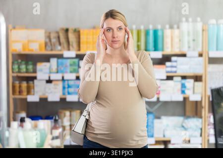 Schwangere Frau mit Kopfschmerzen in Drogeriemärkten Stockfoto