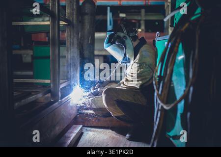 Eine Makroaufnahme mit Fokus auf den Kontaktpunkt beim Metallschweißen. Ein brillanter Anstoß von weißem und blauem Licht dominiert das Zentrum, umgeben von einem Sp Stockfoto