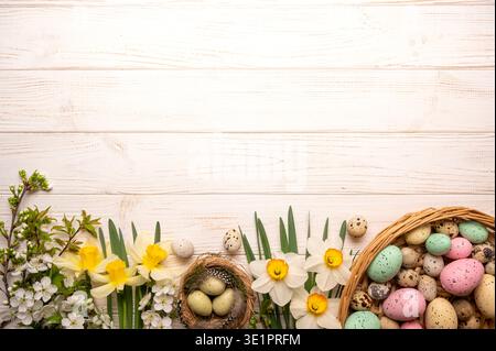 Frühlingsblumen und bunte Eier sind wunderschön auf einer Holzoberfläche angeordnet. Diese Einstellung zeigt ein Nest mit Eiern und einen Korb mit hellen Eiern. Stockfoto