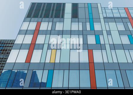Farbenfrohe Fenstermuster sind in einem modernen Gebäude in einer urbanen Umgebung zu sehen. Die Struktur verfügt über eine Mischung aus Glas und leuchtenden Farben, die Ihnen stehen Stockfoto