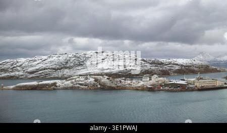 Hintergrund, Berg und Meer mit Hafenstadt im Winter für ästhetische Landschaft oder bewölkten Morgen. Bewölkter Himmel, Meer und Schnee mit Seehafen im Freien Stockfoto