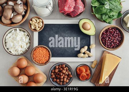 Gesunde Lebensmittel, die Vitamin B5 (Acidum pantothenicum) enthalten. Natürliche Vitamin-B5-Quellen auf hellem Hintergrund mit Tafel, Draufsicht. Stockfoto