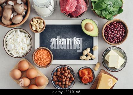 Gesunde Lebensmittel, die Vitamin B5 (Acidum pantothenicum) enthalten. Natürliche Vitamin-B5-Quellen auf hellem Hintergrund mit Tafel, Draufsicht. Stockfoto