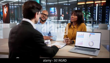 Finanzberater erklärt Einem jungen Paar, das ein Notebook verwendet, Investitionspläne Stockfoto
