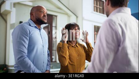 Nachbarn Streiten Lautstark An Der Wohnungstür Und Zeigen Konflikte Im Familienleben. Ein gestresstes Paar, das drinnen steht Stockfoto