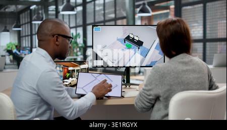 Junger Designer Und Agent, Der Computer Für Umbaupläne Benutzt. Zwei Personen Analysieren Virtuelle Grundrisse Stockfoto