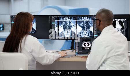 Zwei Ärzte untersuchen Röntgenbilder sorgfältig auf Einem Computerbildschirm und besprechen Behandlungsoptionen Stockfoto