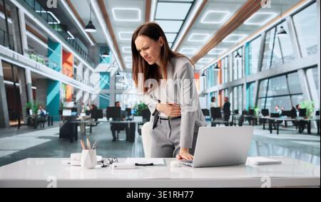 Frau Mit Bauchbeschwerden Und Entzündungen Während Der Arbeit Im Büro Stockfoto