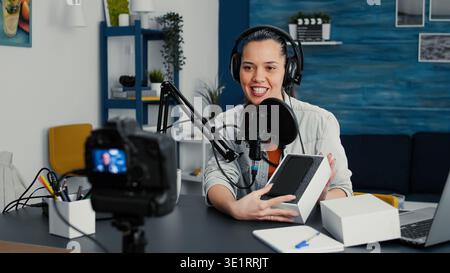 Beliebte Internet-Influencer tun Auspacken Video von modernen Smartphone. Kreativer Entwickler digitaler Inhalte präsentiert dem Publikum ein mobiles Touchscreen-Gerät und prüft dabei die Spezifikationen. Stockfoto