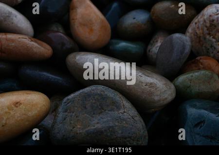 Ein professionelles Makrofoto eines mit Kieselsteinen bedeckten Ufers. Das Bild zeigt eine dichte Ansammlung von abgerundeten, wasserabgetragenen Steinen in verschiedenen Größen und Farbtönen Stockfoto