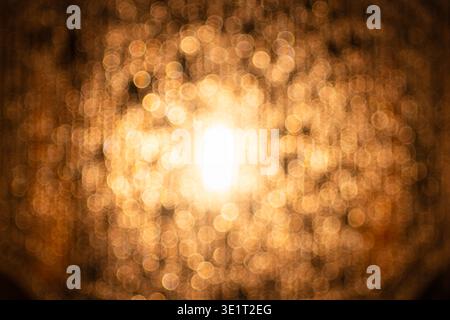 Abstrakter goldener Bokeh-Hintergrund mit weichen, verschwommenen Lichtkreisen und einer hellen Mitte. Perfekt für elegante Urlaubs-, Luxus- und Festthemen Stockfoto