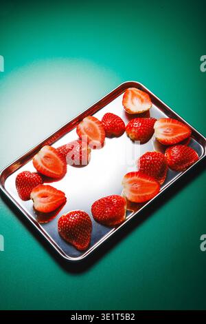 Frische Erdbeeren auf reflektierendem Tablett grünem Hintergrund Stockfoto