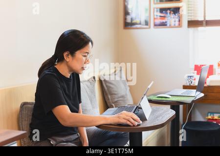 Konzentrierte Frau, die im Café am Laptop arbeitet. Stockfoto