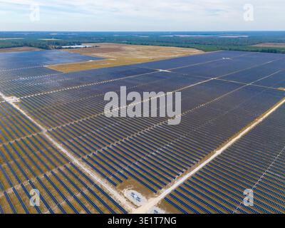 Aus der Vogelperspektive schimmernde Solarpaneele, die sich über die Landschaft erstrecken und unter einem riesigen Himmel den Horizont treffen, Jasper, Florida, USA. Stockfoto