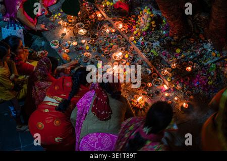 Frauen in farbenfrohen Saris knien in Udaipur auf dem Boden, um während einer traditionellen religiösen Zeremonie in der Nacht zahlreiche kleine Öllampen anzuzünden. Stockfoto
