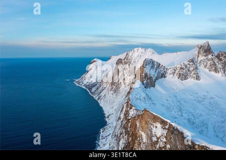 Aus der Vogelperspektive auf eine dramatische Küste, wo die schneebedeckten Berge auf das tiefblaue Meer treffen, Lofoten, Nordland, Norwegen. Stockfoto