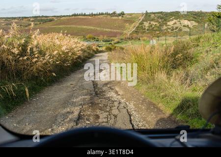 Blick aus einem Camper Cockpit durch die Windschutzscheibe auf eine sehr schmale und steile Straße in sehr schlechtem Zustand die durch die Landschaft von Apulien führt. Apulien, Italien. Blick auf eine schmale Straße in sehr schlechtem Zustand im Hinterland von Apulien. *** Blick von einem Wohnmobil-Cockpit durch die Windschutzscheibe auf eine sehr schmale und steile Straße in sehr schlechtem Zustand, die durch die Landschaft von Apulien Apulien, Italien führt Blick auf eine schmale Straße in sehr schlechtem Zustand im Hinterland von Apulien Stockfoto
